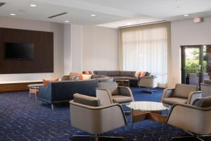 Courtyard by Marriott Lubbock Downtown/University Area في لوبوك: غرفة انتظار فيها كنب وكراسي وشاشة عرض