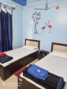 dwa łóżka w pokoju z ptakami na ścianie w obiekcie Maity lodge w mieście Gangtok