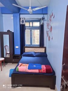 a bedroom with a bed with blue walls and a window at Maity lodge in Gangtok