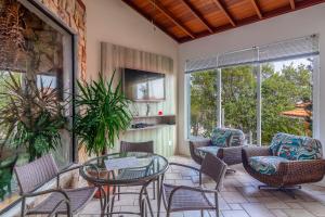 eine Terrasse mit Stühlen, einem Tisch und einem TV in der Unterkunft Jurerê Ocean Flats in Florianópolis