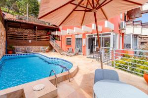 a swimming pool with an umbrella and chairs at Jurerê Ocean Flats in Florianópolis