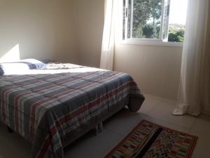 a bedroom with a bed with a blanket and a window at UNIJUI in Ijuí