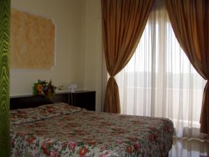 una camera con letto e finestra con tende di Hotel Le Dune a Licola