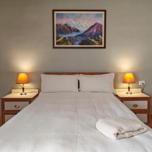 a bedroom with a large white bed with two lamps at Boudha Apart Hotel in Kathmandu
