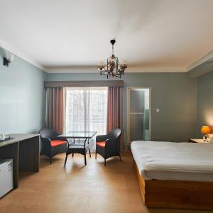 Boudha Apart Hotel في كاتماندو: غرفة نوم بسرير وطاولة وكراسي