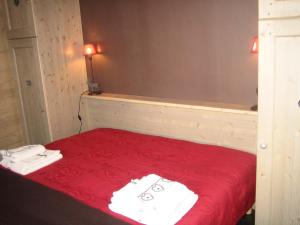 a bedroom with a red bed with towels on it at Charmant appartement avec WiFi et parking privé aux Gets - FR-1-671-79 in Les Gets