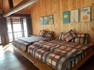 2 łóżka w pokoju z drewnianymi ścianami w obiekcie Hồ Tằm Homestay w mieście Hòa Bình