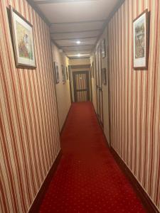 un largo pasillo con alfombra roja y suelo rojo en Le Grand Monarque Donzy, en Donzy
