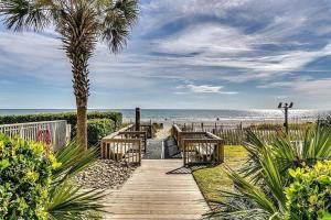 a wooden pathway to the beach with benches and a palm tree at Spectacular Ocean and Coastline Views Condo CB 14th Floor in Myrtle Beach