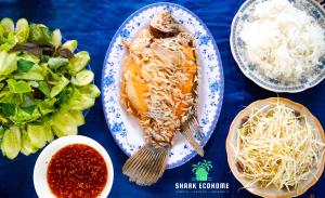een tafel met een bord eten en een salade bij SHARK ECOHOME BẾN TRE in Ấp Phong Phú