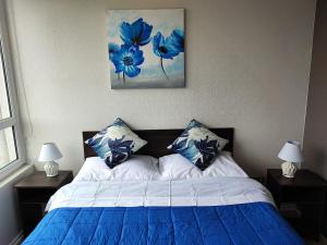 a bedroom with a bed with blue and white pillows at Hermoso departamento en Temuco in Temuco