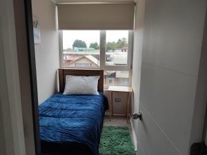 a small bedroom with a bed and a window at Hermoso departamento en Temuco in Temuco