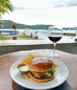um prato com um hambúrguer e batatas fritas e um copo de vinho em Panama Dive Adventure em Colón