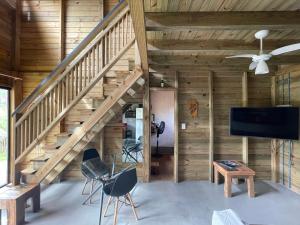 uma sala de estar com paredes de madeira e uma escadaria em Rosa Lodge Lofts em Praia do Rosa