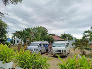 two people standing next to two vans parked in a yard at Cheryl's Place Vacation Home Palawan in Puerto Princesa City