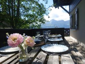 a wooden table with plates and flowers in a vase at Chalet 5 chambres, 9 pers, wifi, 1 animal, non fumeur - FR-1-733-144 in Crest-Voland
