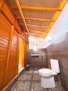 a bathroom with a white toilet in a room at Batur cottage in Kubupenlokan