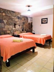 1 dormitorio con 2 camas y pared de piedra en Posada "Jardin Huasteca Xilitla", en Xilitla