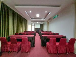 um quarto com cadeiras vermelhas, mesas e cortinas em HEMRA HOTEL em Balikpapan