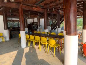 ein Restaurant mit gelben Stühlen und einer Bar in der Unterkunft Hồ Tằm Homestay in Hòa Bình