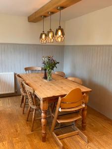 einen Holztisch mit Stühlen und eine Vase mit Blumen darauf in der Unterkunft Cottage in the Heart of Frome in Frome