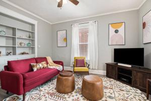 a living room with a red couch and a tv at Game/Theater Room - Barbecue - Central Location in Omaha