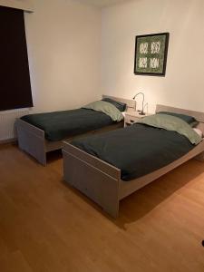 two twin beds in a room with a table at Ruim 2 slaapkamer appartement dichtbij Antwerpen, haven en natuur in Brasschaat