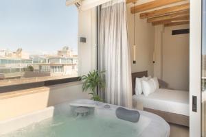 Habitación de hotel con bañera y dormitorio en Living Stone Condo Hotel, en Atenas