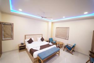 1 dormitorio con 1 cama y 2 sillas azules en Saffron Inn, Bhiwara, en Bhīlwāra