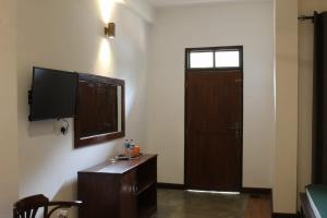 Cette chambre dispose d'une télévision et d'une porte avec une table. dans l'établissement Forest edge villa, à Anurâdhapura