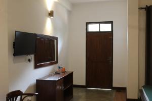 a room with a television and a door with a table at Forest edge villa in Anuradhapura