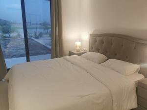 une chambre avec un lit blanc avec une grande fenêtre dans l'établissement Hawana VIP Private Apartment, à Wādī Khasbar