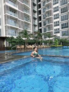 a woman sitting in a swimming pool in a hotel at THE PALLADIUM- Serene in Iloilo City