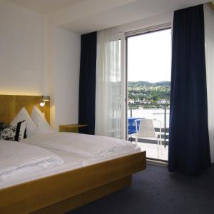 um quarto de hotel com uma cama e uma porta de vidro deslizante em Hotel Garni Ogris Am See em Velden am Wörthersee