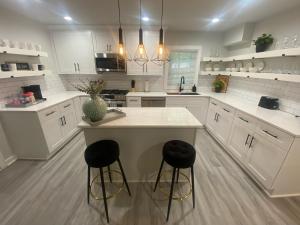 a kitchen with white cabinets and a island with two stools at East Point Atlanta - Spacious 5BR Retreat! in Atlanta