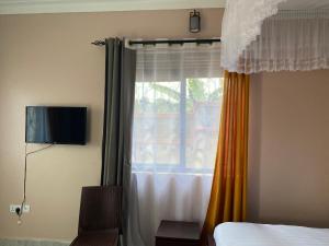 1 dormitorio con 1 cama y una ventana con cortinas en Zoe heights villas, en Kalungu