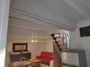 a living room with a staircase and a red couch at Maison 4 personnes in Caillac