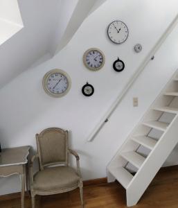 um quarto com relógios na parede e uma cadeira em L Heure Bleue em Wezembeek-Oppem