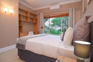 a bedroom with a large white bed and a window at Menlyn Maine - The Smart Home in Pretoria +63 photos