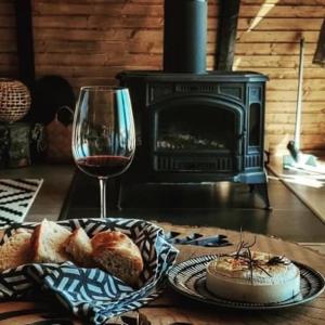 a plate of bread and a glass of wine on a table at Nordik Cabin - Aframe with 2 bedrooms in Mărişel