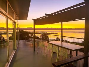 uma varanda com mesa e cadeiras e um pôr-do-sol em Stunning Views over Tasman Bay em Nelson