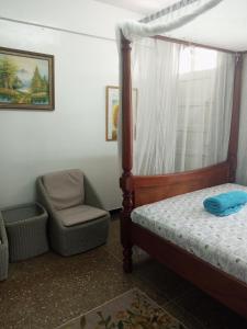 1 dormitorio con 1 cama y 1 silla en Paradise Apartment en Mombasa