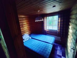 Habitación pequeña con cama azul en una cabaña de madera. en Kalliorinteen Mökit Suvipirtti, en Töysä