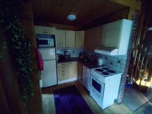 - une petite cuisine avec des appareils blancs et des armoires en bois dans l'établissement Kalliorinteen Mökit Suvipirtti, à Töysä