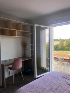 a bedroom with a desk and a sliding glass door at Chambre d'hôte la vallée Fermante 