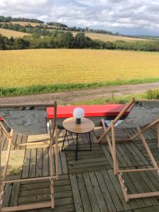 a table and chairs on a deck with a view of a field at Chambre d'hôte la vallée Fermante 