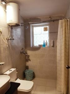 La salle de bains est pourvue de toilettes, d'une douche et d'une fenêtre. dans l'établissement Krishna Nivaas Homestay, à Vrindavan