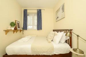 a bedroom with a bed with white sheets and a lamp at Spacious 2 bedroom Apartment In Holborn in London