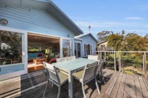 a blue house with a table and chairs on a deck at Blue on Collins in Merimbula