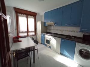 a kitchen with blue cabinets and a table and a washing machine at Apartment with parking "Hola Oviedo" in Oviedo